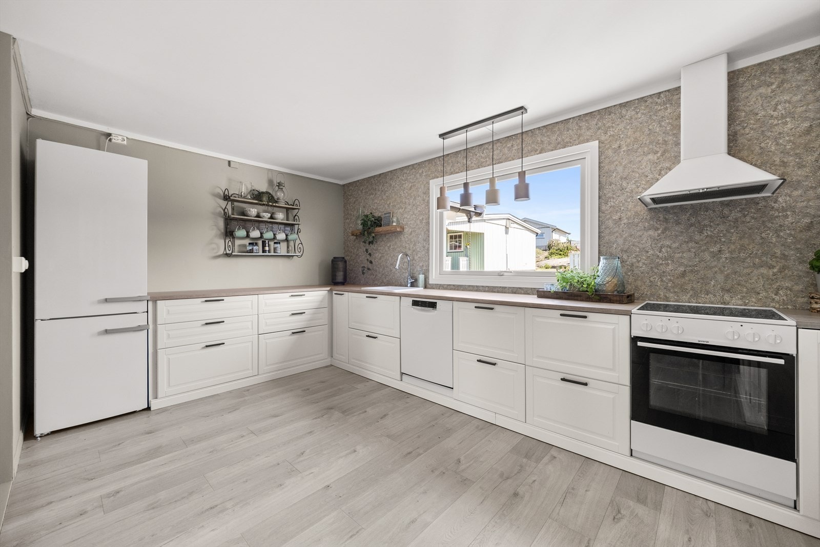 Kjøkkenet er innredet med klassisk IKEA-innredning med hvite, profilerte fronter og laminert benkeplate. Rommet har en praktisk U-form som gir rikelig med arbeids- og oppbevaringsplass. Galleribilde