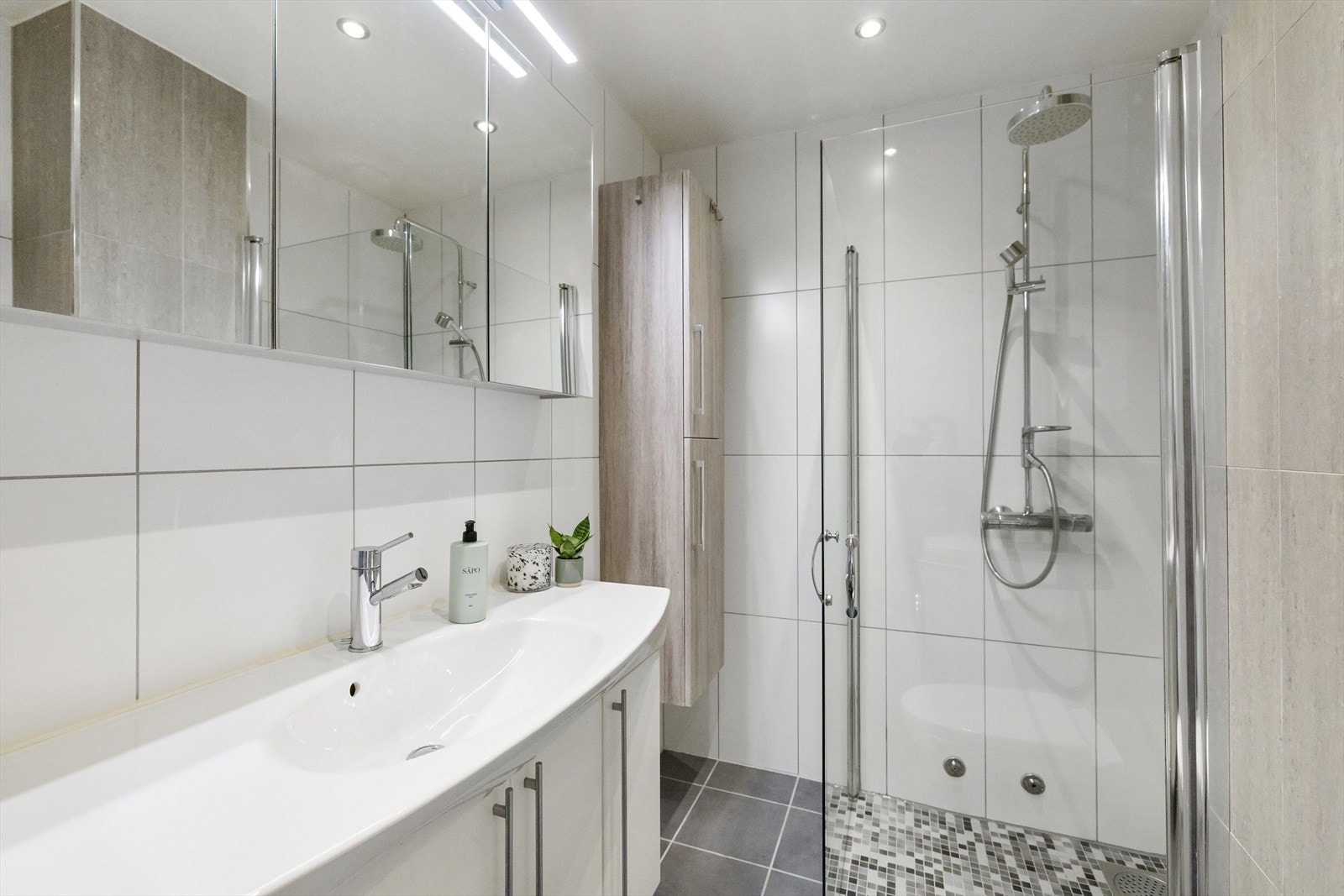 Badet er utstyrt med innfellbare dusjdører, veggmontert toalett og servantskap med ettgreps blandebatteri fra Mors. Galleribilde