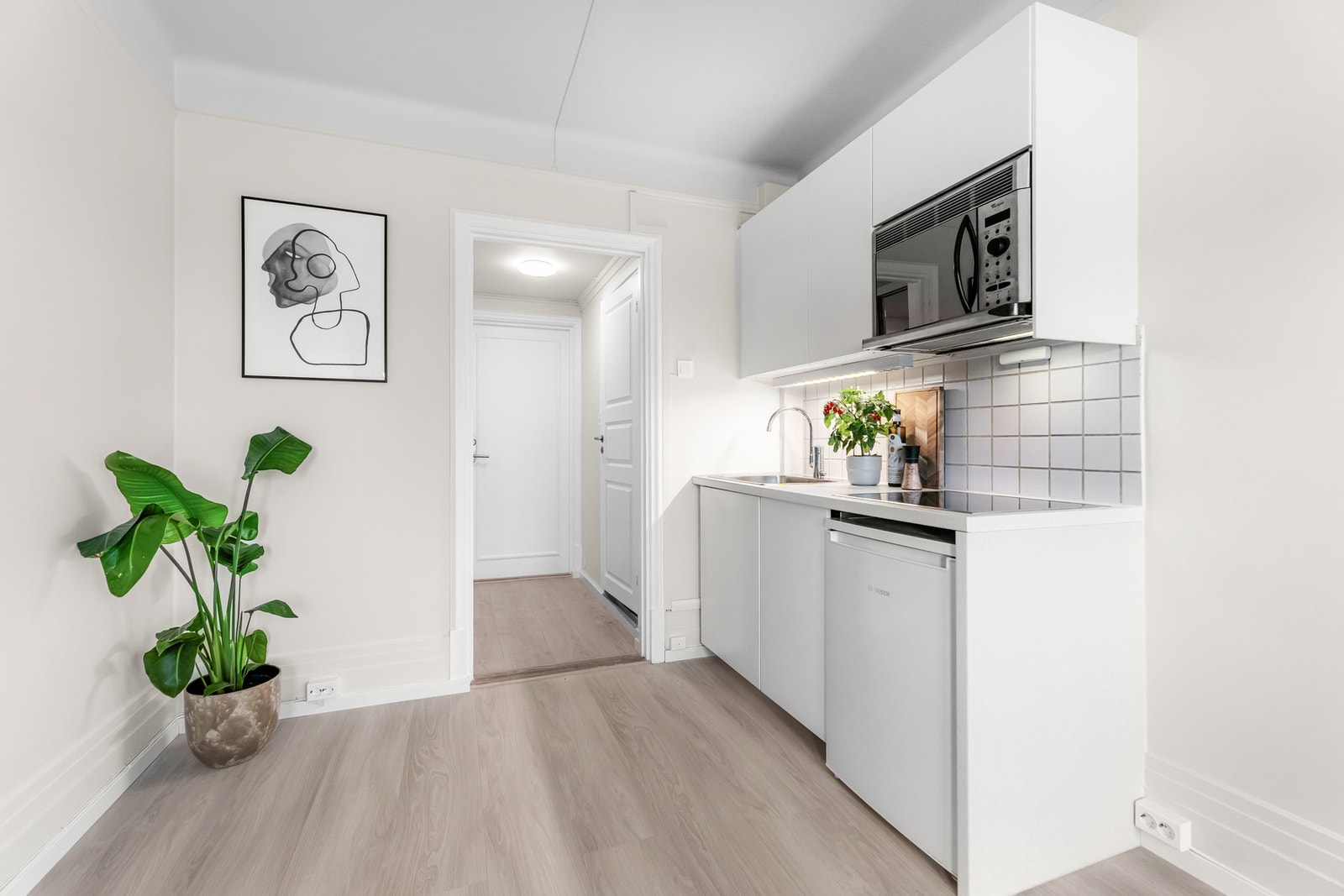 Kjøkkeninnredning med glatte fronter med laminat benkeplate, samt
integrerte hvitevarer og plass til kjøleskap (benk modell). Galleribilde