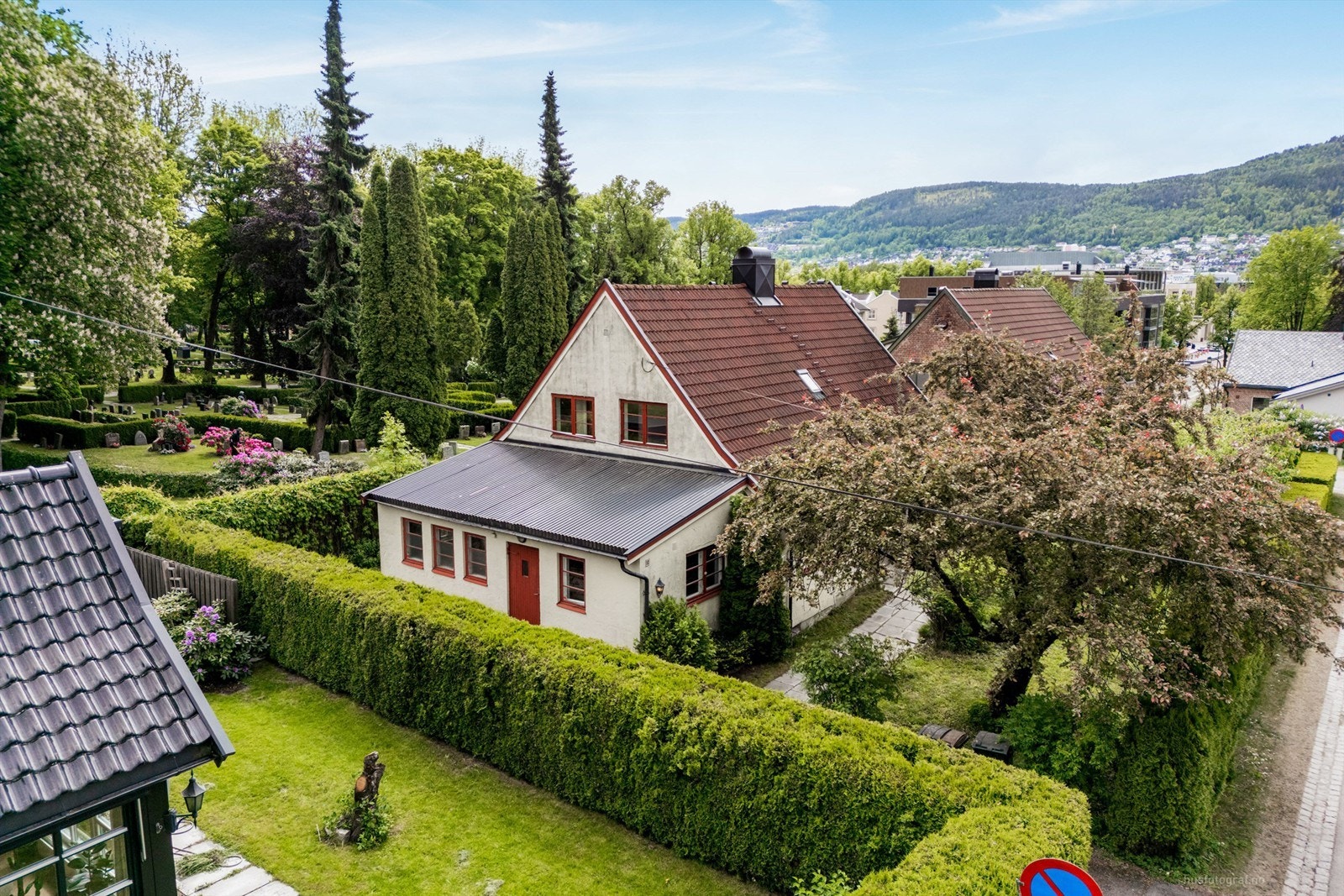 Tilnærmet flat tomt som er opparbeidet med gressplen, hekk, prydbusker, trær og diverse beplantninger Galleribilde