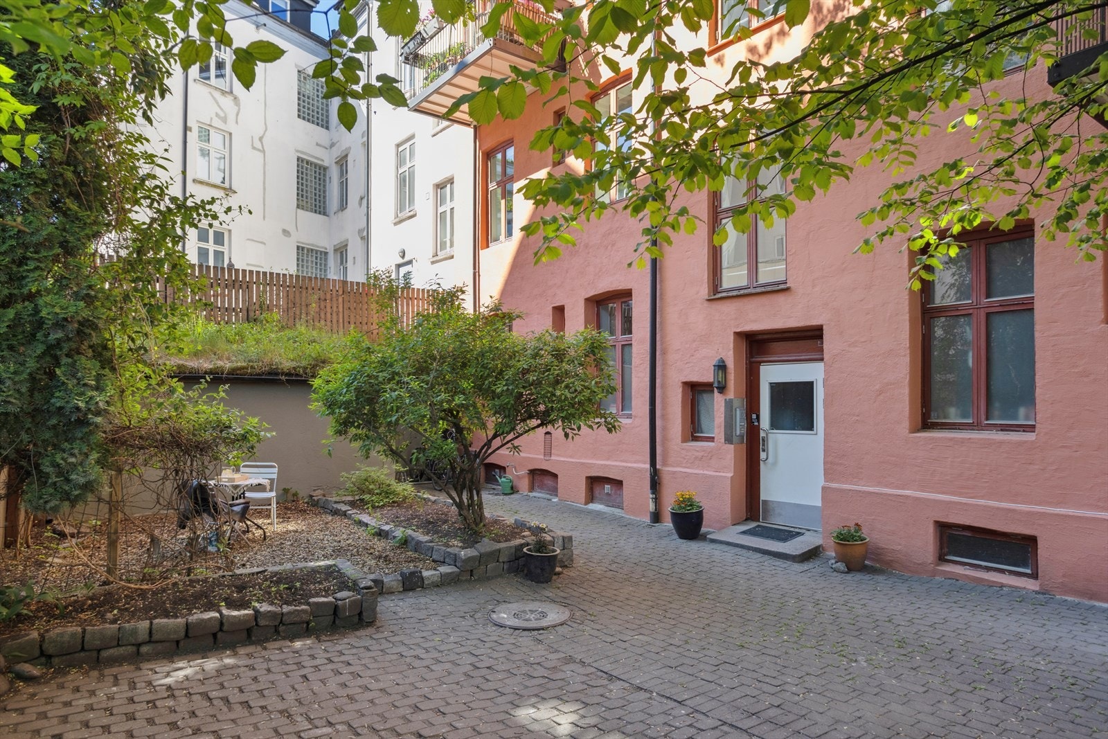 Hyggelig felles bakgård med belegningsstein, sittegruppe, trær og beplantning. I bakgården er det en felles bod til oppbevaring av sykler. Galleribilde