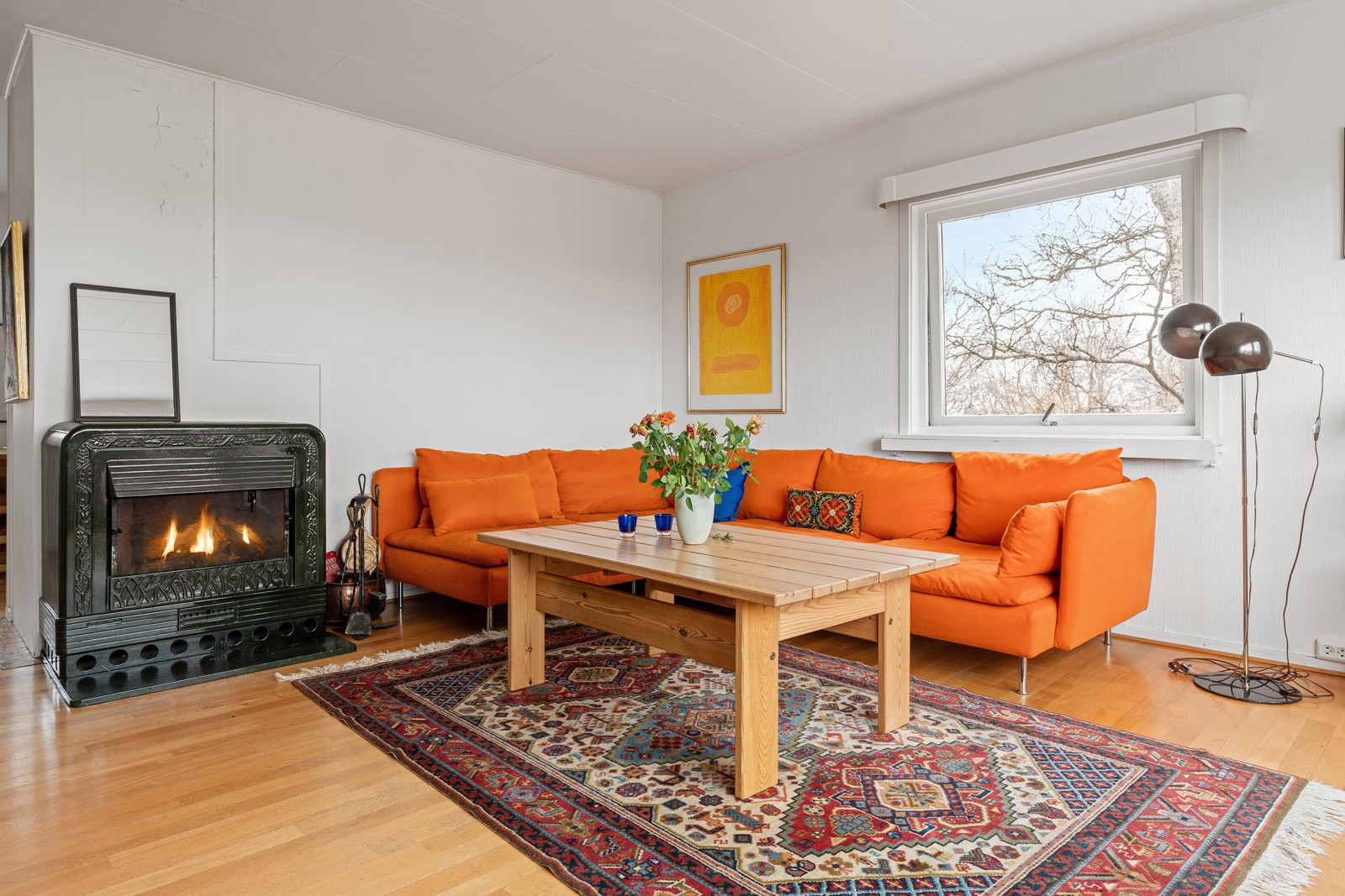Stuen har vedovn, som innbyr til hygge i sofakroken.