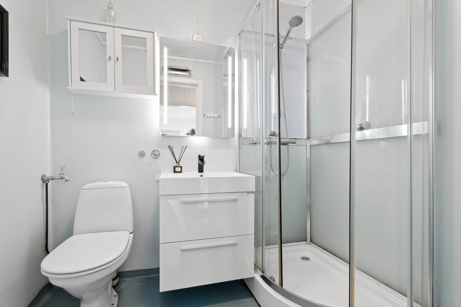 Det eldre våtrommet har praktisk belegg på både gulv og vegger. Badet er innredet med en servant med underskap som ble oppgradert med ny baderomsinnredning og speil i 2018. Galleribilde