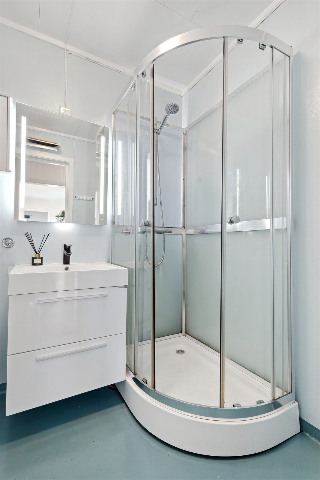 Badet er utstyrt med dusjkabinettet og gulvmontert wc og rommet varmes opp av en stråleovn. Galleribilde