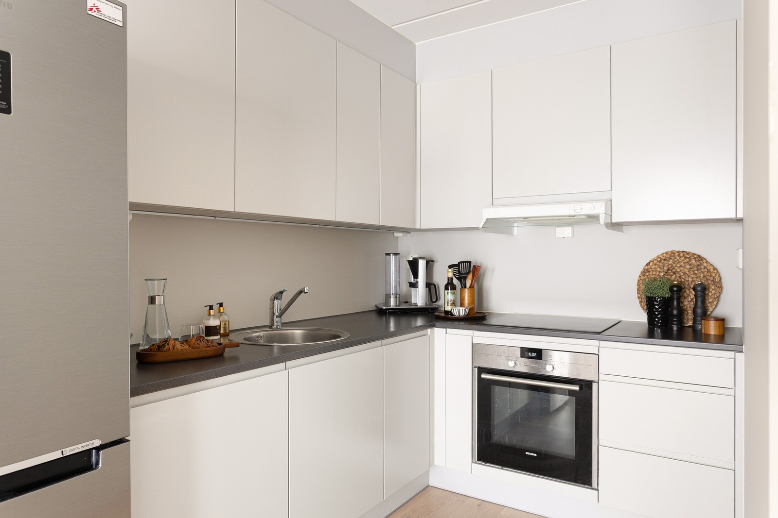 Kjøkkeninnredningen har fabrikklakkerte glatte fronter og laminat benkeplate med nedfelt oppvaskkum og nedfelt induksjon koketopp. Galleribilde