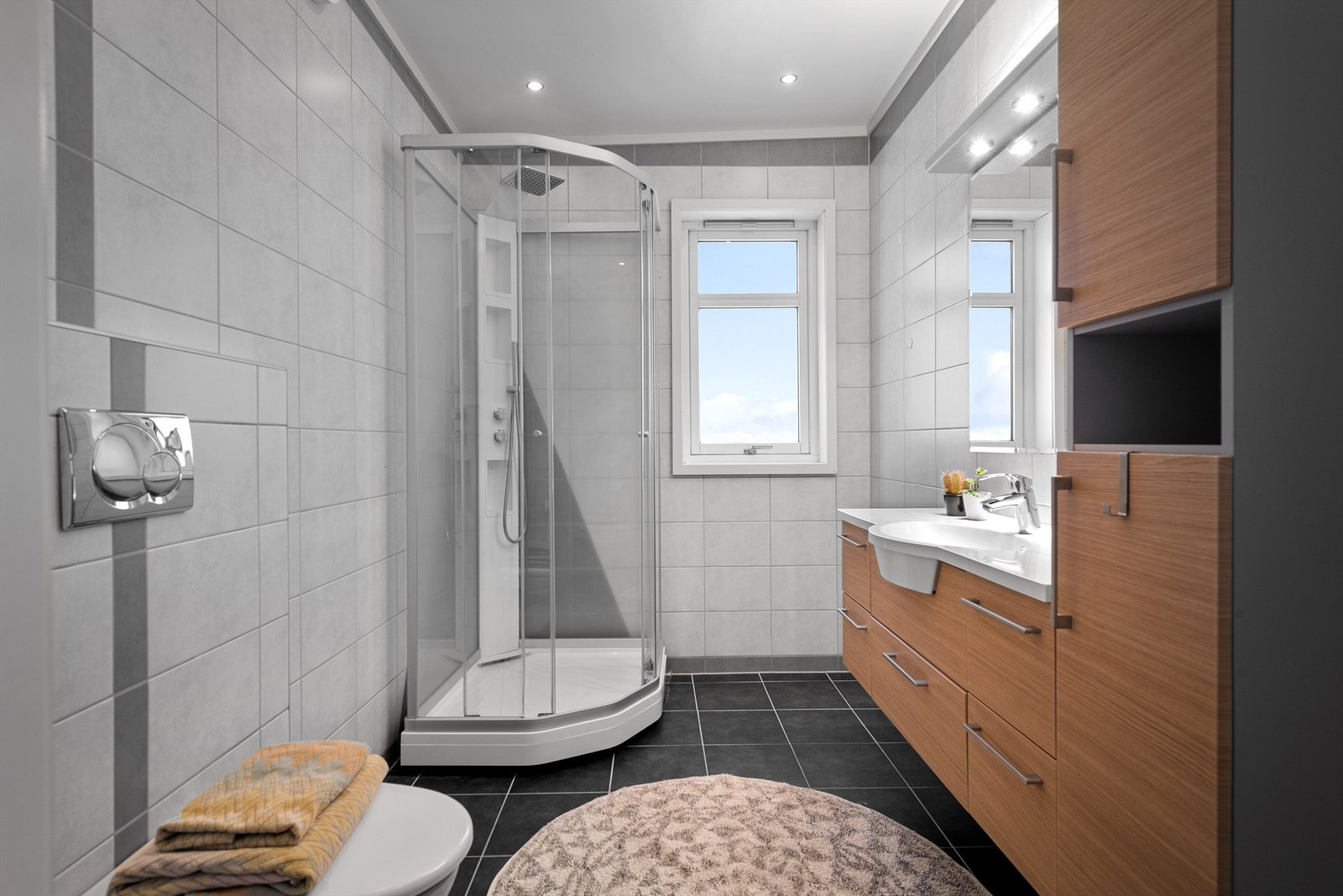 Flislagt bad med dusjkabinett. Mye skap- og skuffeplass i baderomsinnredningen. Galleribilde