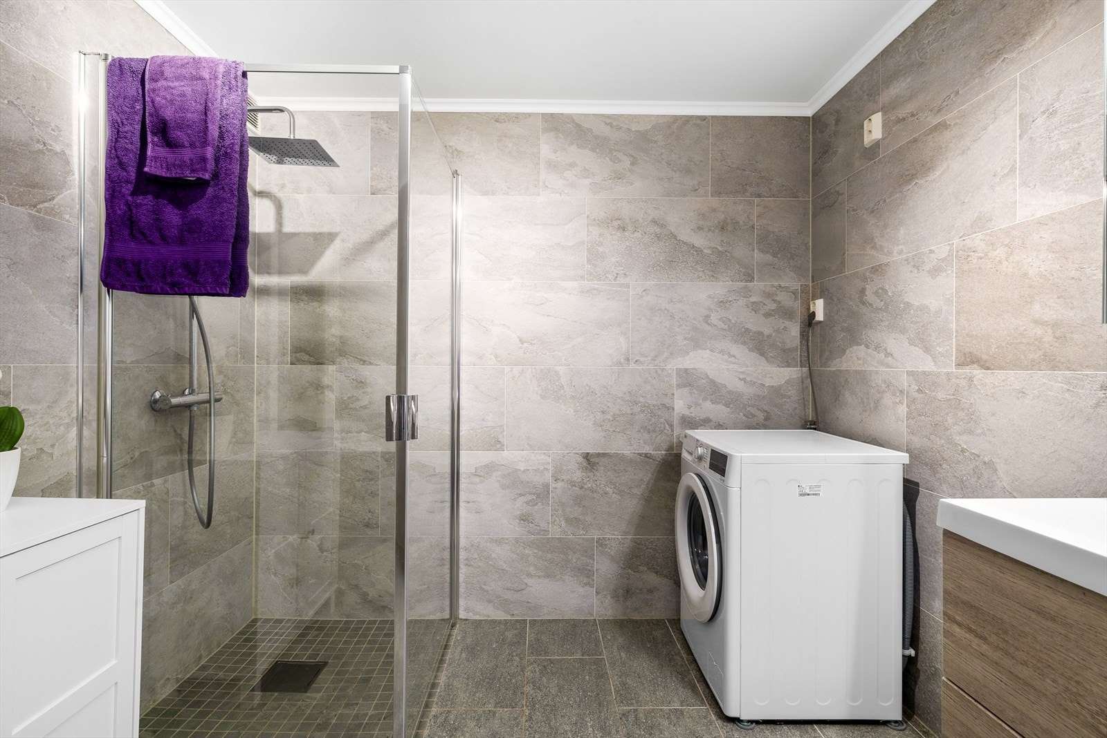 Flislagt baderom med tidløst og moderne uttrykk. Badet er innredet med nedfelt servant i et stilrent servantskap som gir god oppbevaringsplass, samt speilskap med integrert belysning. Det er opplegg for vaskemaskin. Galleribilde