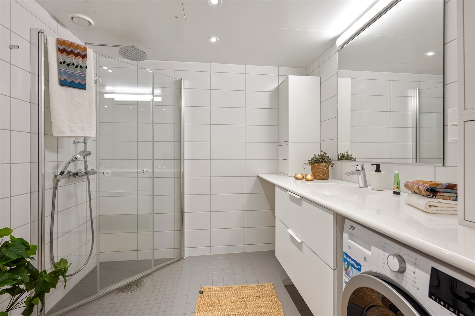 Flott flislagt dusjbad med gulvvarme. Vegghengt toalett og pen skapinnredning med fin plass til vaskemaskin. Galleribilde