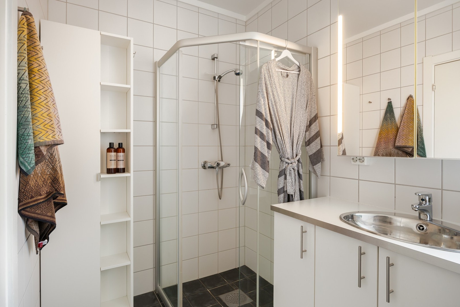 Flislagt baderom med dusjhjørne, vegghengt toalett, gulvvarme, og innredning med servant. Galleribilde