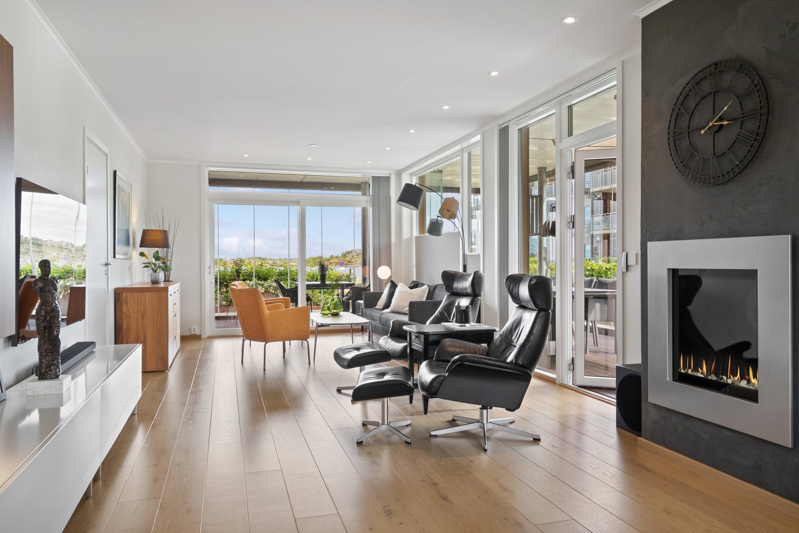 Stuen ligger vendt mot sjøen og har imponerende vindusflater med brede skyvedører i glass ut til den innglassede terrassen. Galleribilde