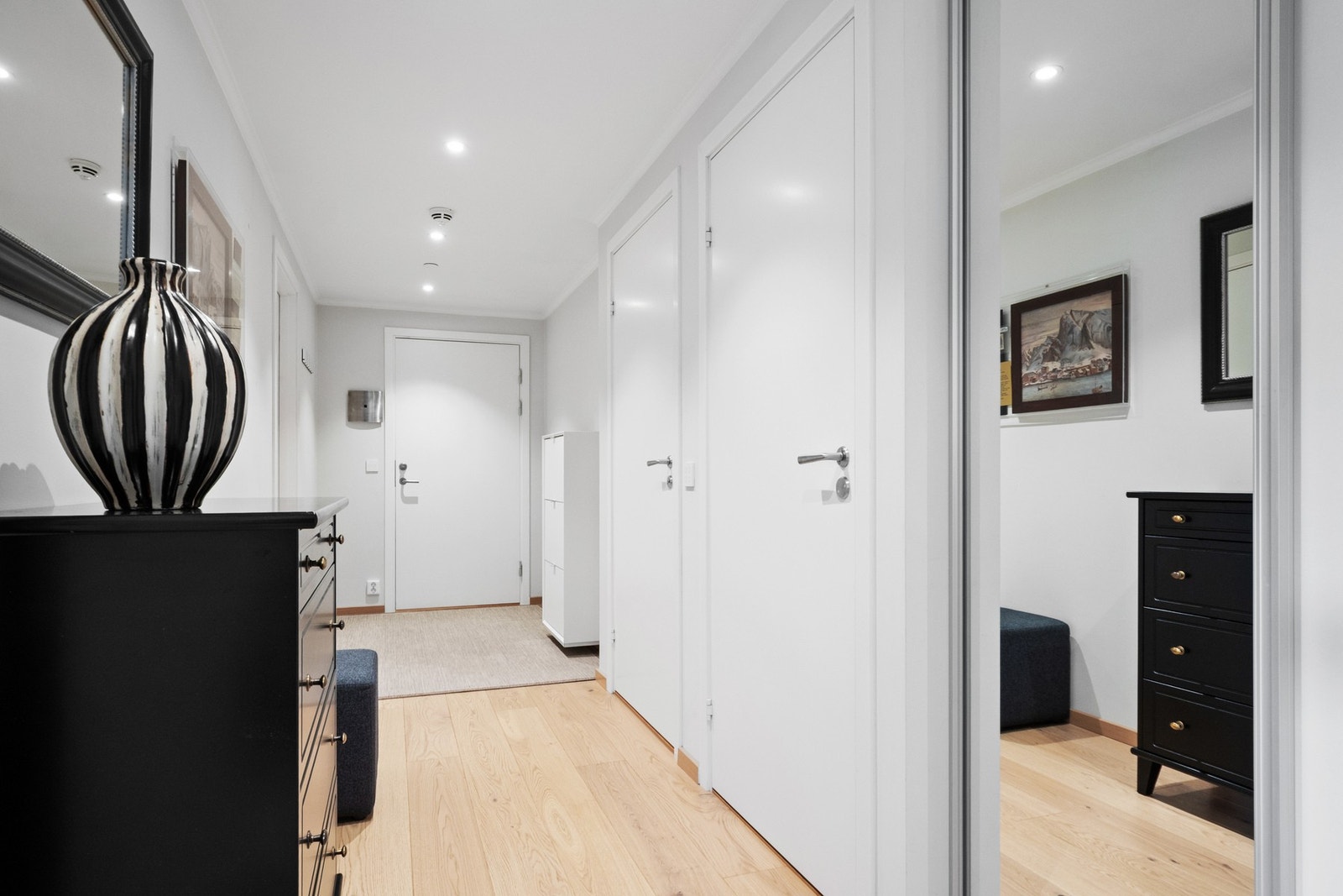 Entreen gir et ryddig og gjennomført førsteinntrykk, med lysegrå vegger, downlights og lun, enstavs parkettgulv med vannbåren varme. Galleribilde