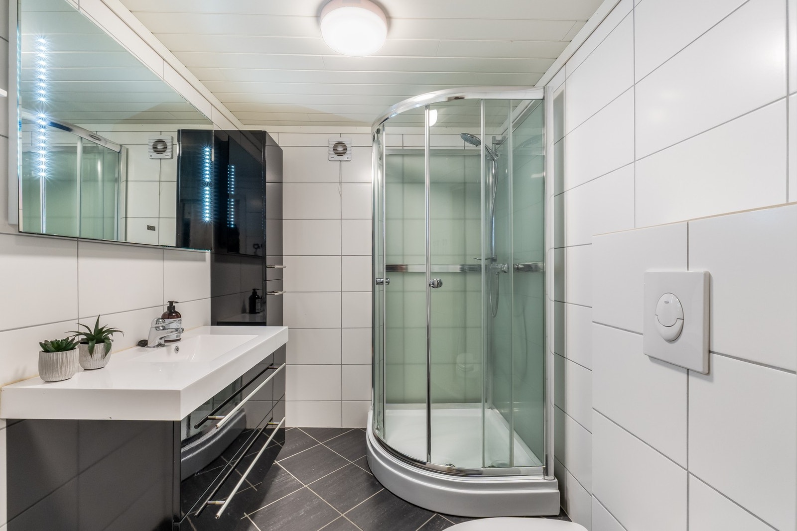 Badet i underetasjen har flislagte gulv og vegger, samt panel i taket, som gir et moderne uttrykk. Galleribilde