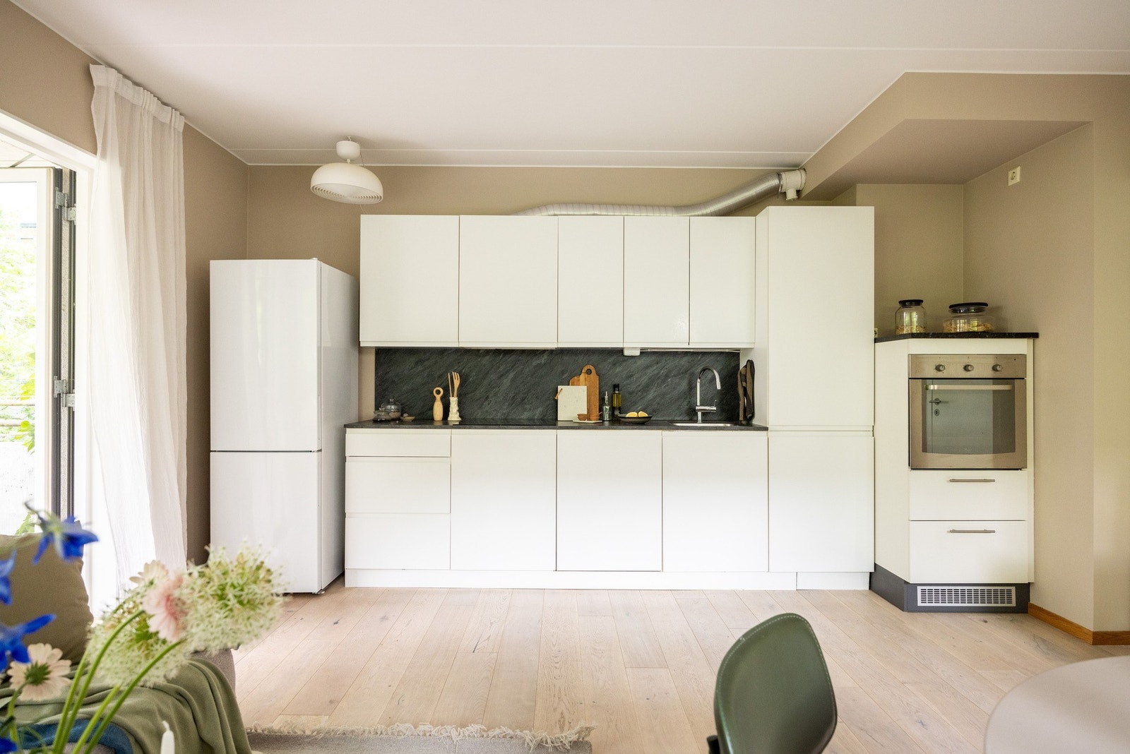 Pen og moderne kjøkkeninnredning fra Kvik med lyse fronter og benkeplate i laminat. Galleribilde