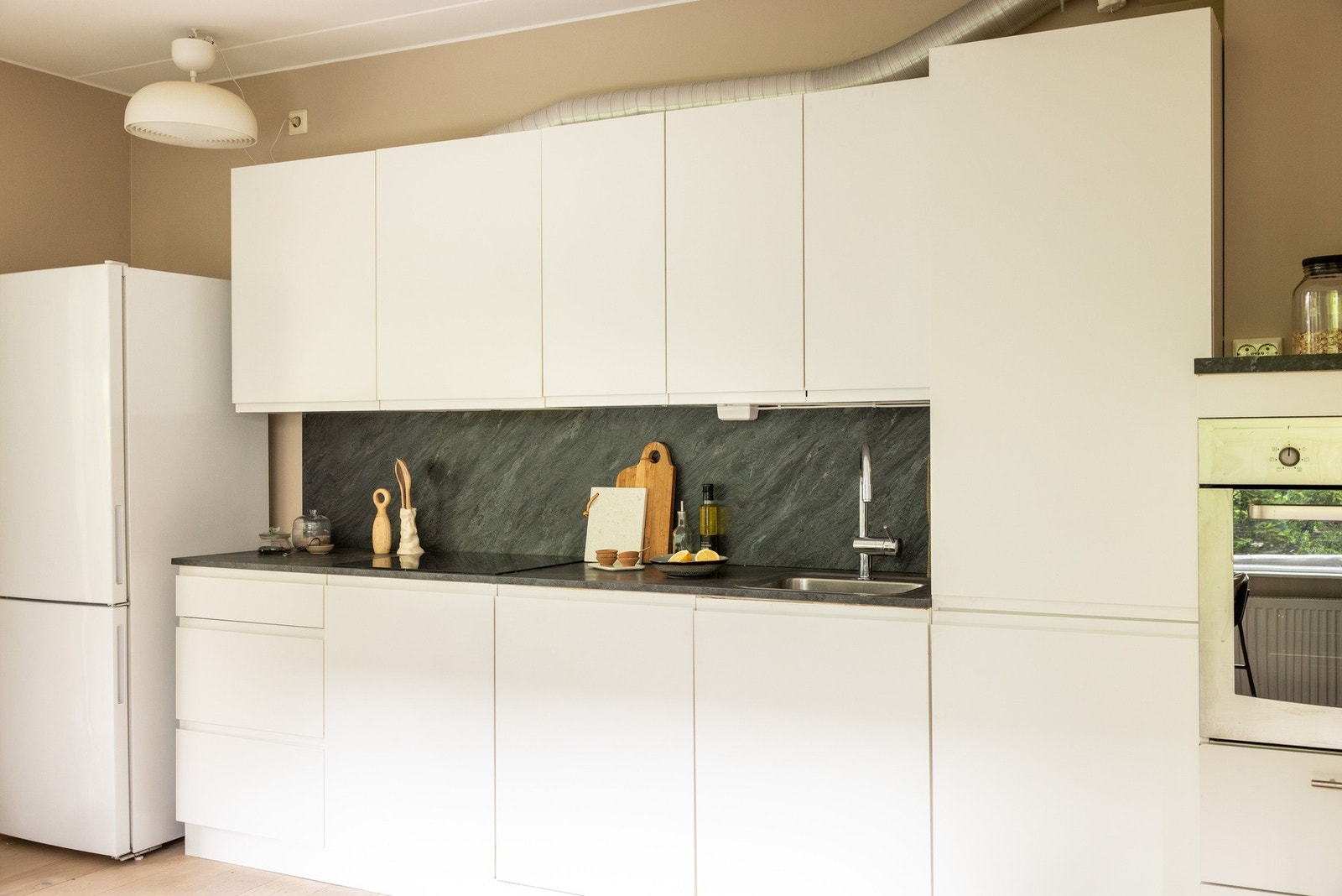 Integrerte hvitevarer som induksjonsplatetopp, stekeovn og oppvaskmaskin. Frittstående kjøleskap med frys. Galleribilde