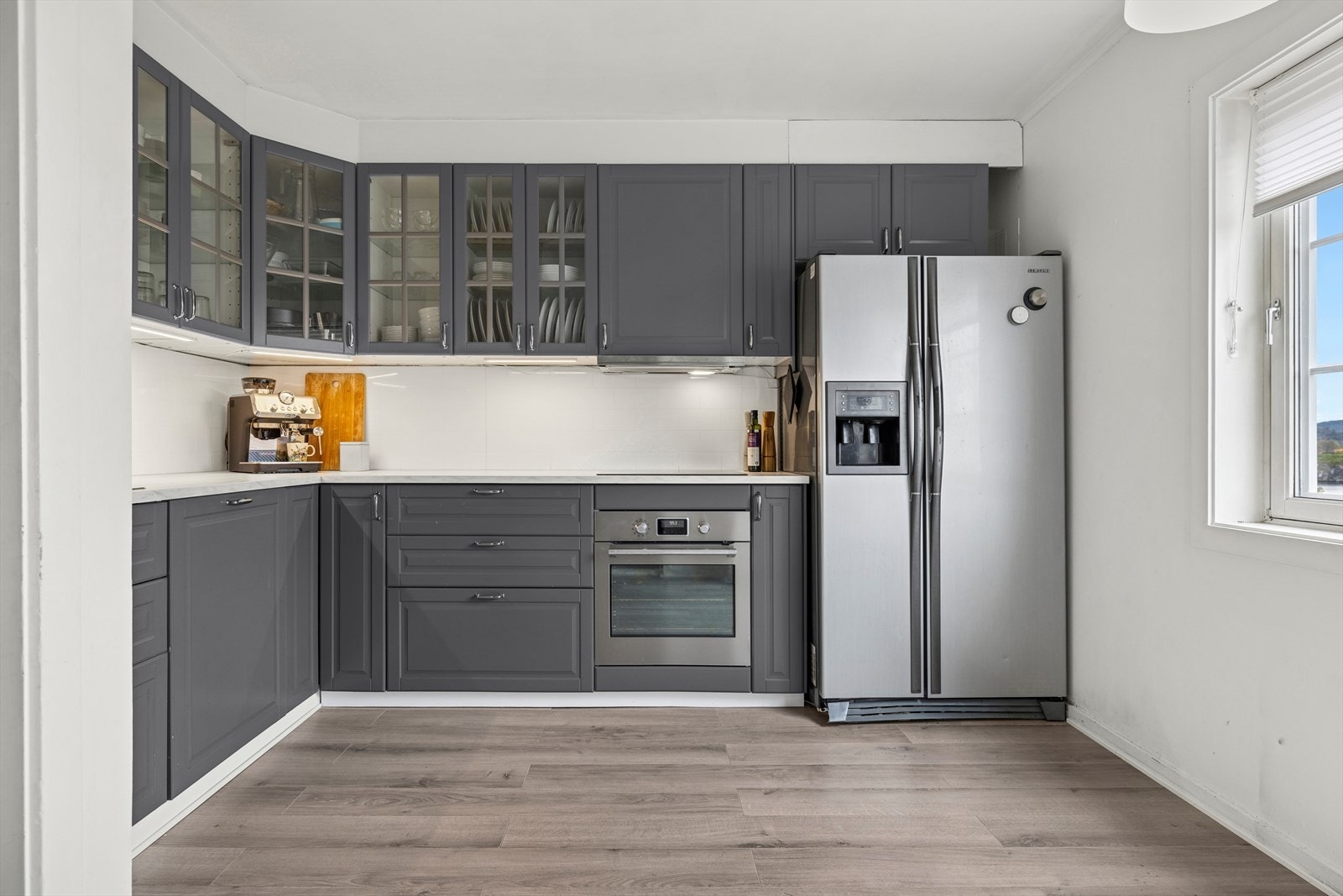 Pen kjøkkeninnredning fra 2018 med integrert komfyr med platetopp og oppvaskmaskin, samt frittstående kjøleskap Galleribilde