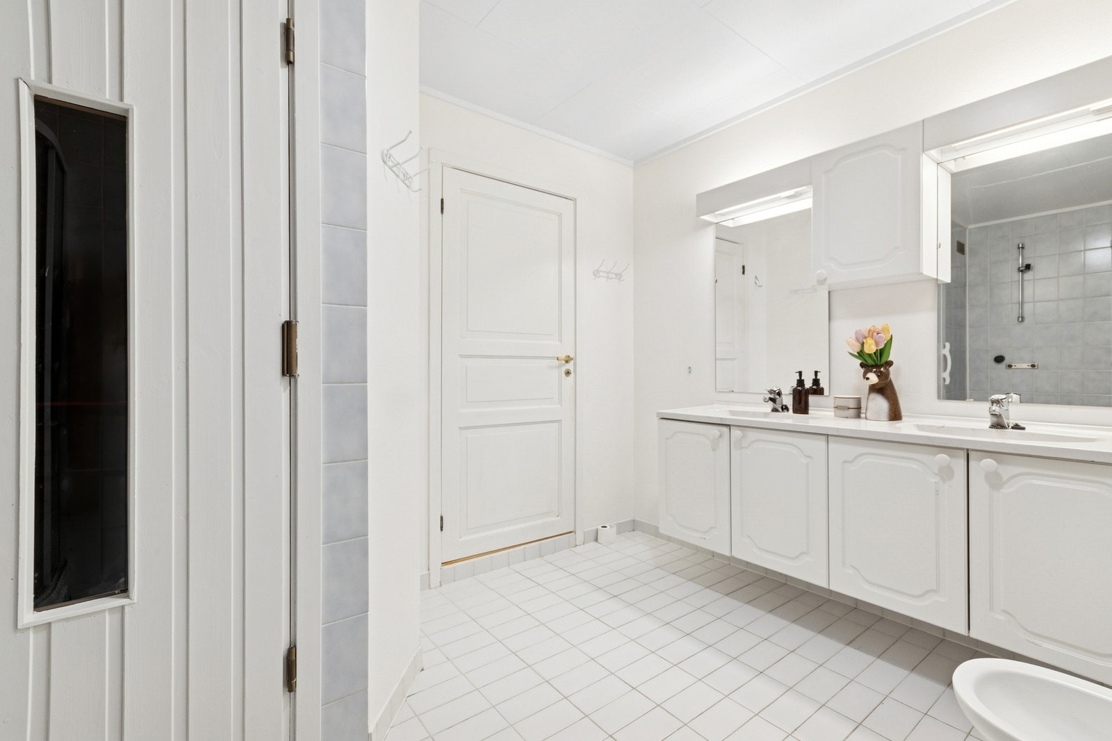 Badet i underetasjen har flislagt gulv og våtromsstrie på vegg. Innredning med to nedfelte servanter, dusjkabinett, toalett og bidé. Elektriske varmekabler i gulv. Galleribilde