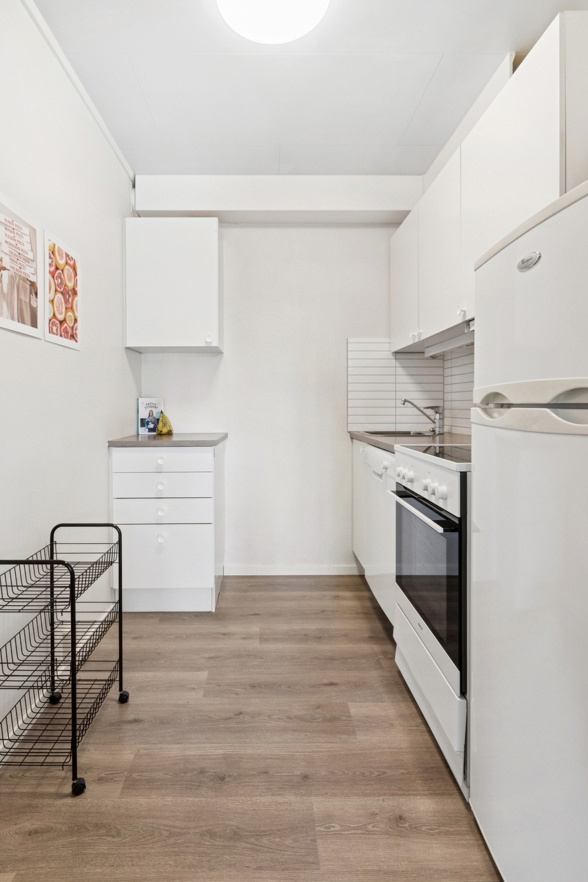 Kjøkken med hvite, slette fronter og benkeplate i laminat med kitchenboard over benk. Galleribilde