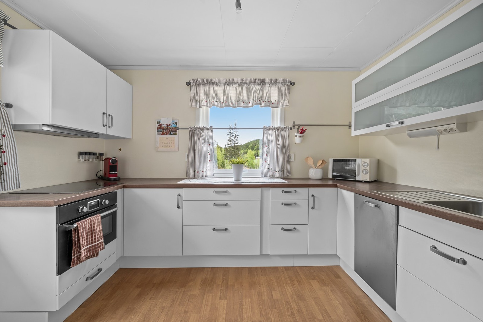 Hvit kjøkkeninnredning med glatte fronter og laminert benkeplate. Galleribilde