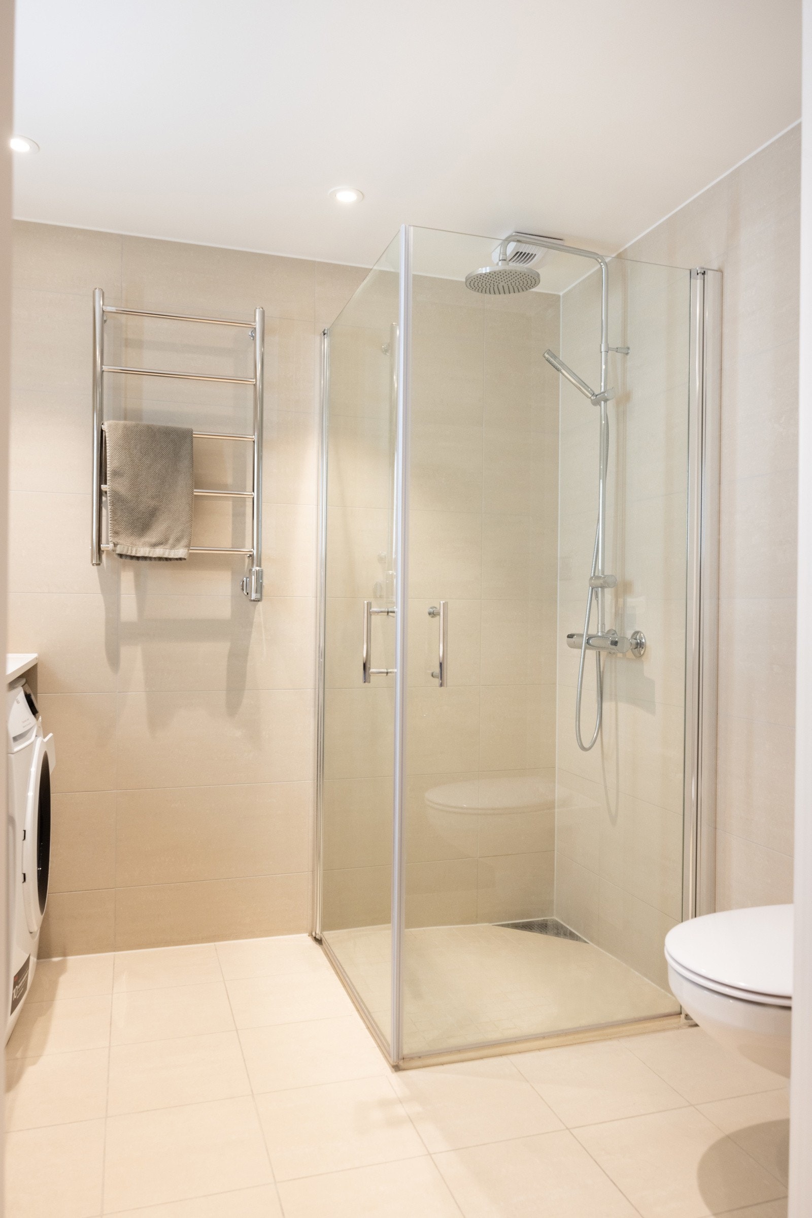 Baderommet har dusjhjørne med glassdører, vegghengt toalett og praktisk baderomsinnredning med nedsunket servant, speil og integrert belysning. Galleribilde