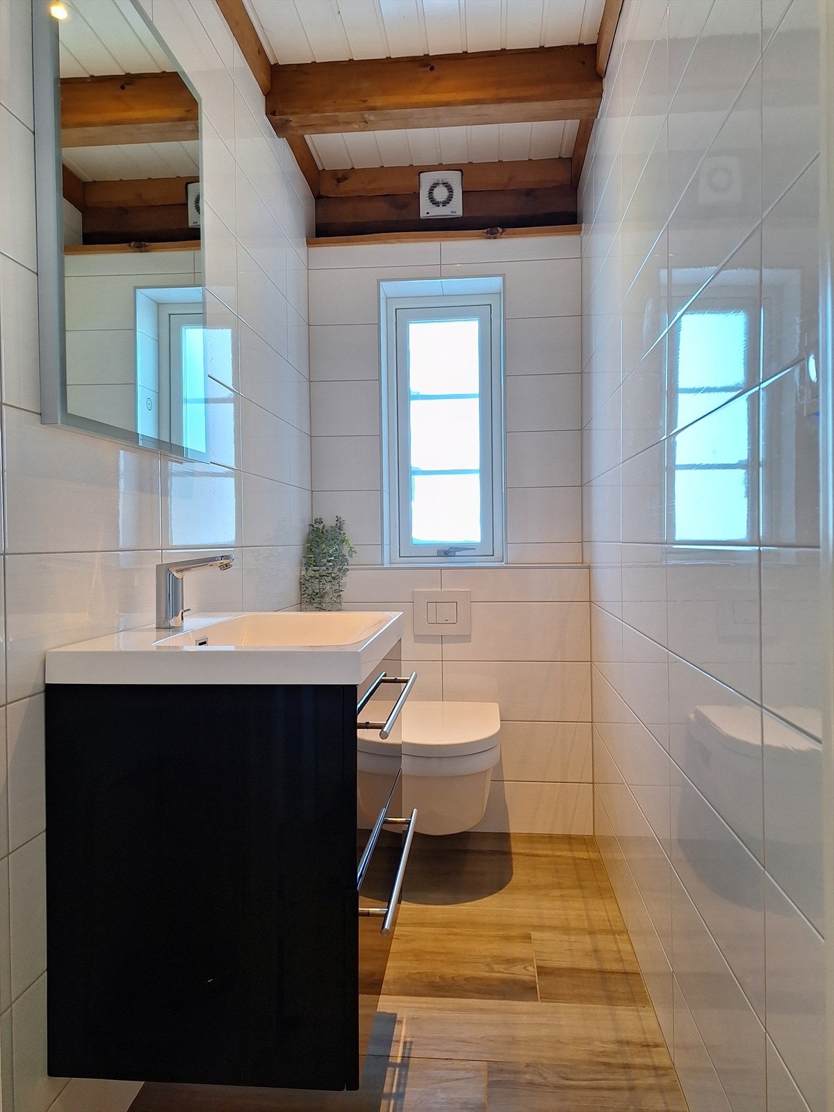 Helfliset toalettrom med gulvvarme. Innredet med vegghengt toalett og vegghengt servantinnredning med skuffer og ovenpåliggende servant. Galleribilde