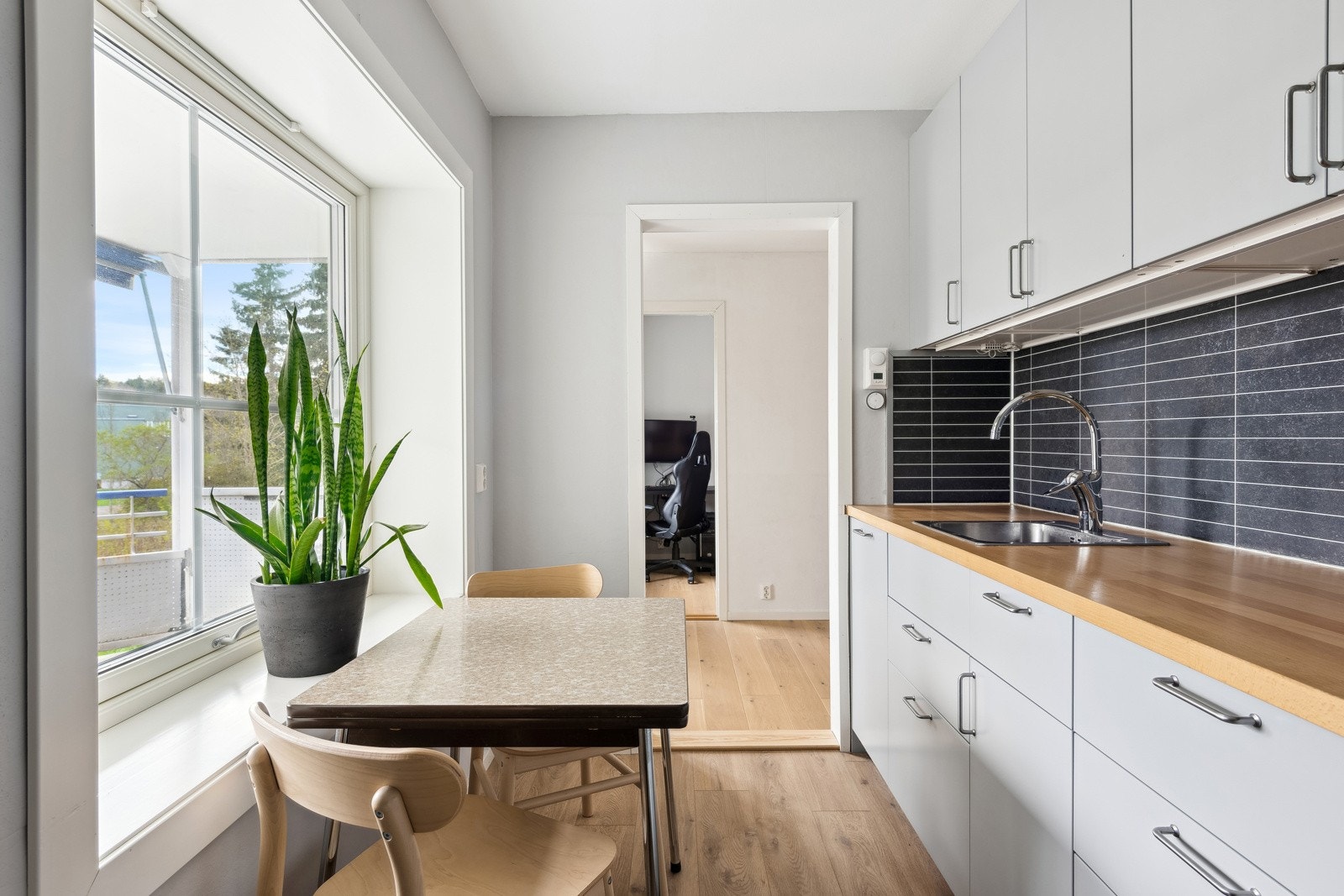 Kjøkken med plass til spisebord ved kjøkkenvindu. Galleribilde