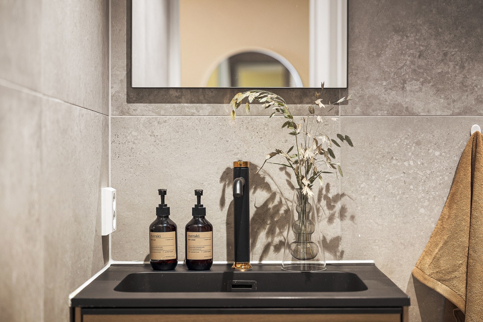 Badet er innredet med vegghengt toalett, dusjhjørne med glassdører, veggskap og servant med innredning/speil/belysning. Galleribilde