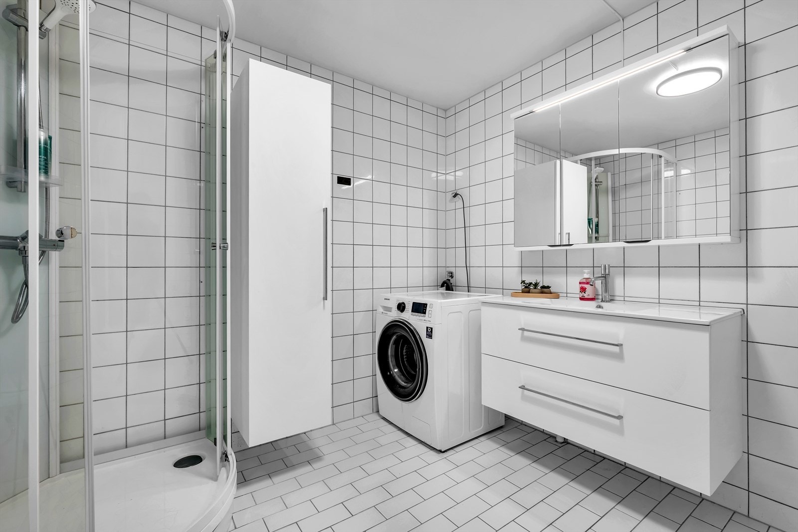 Badet er innredet med nedfelt servant med rom for oppbevaring i underskap, speil, toalett og dusjkabinett. Galleribilde