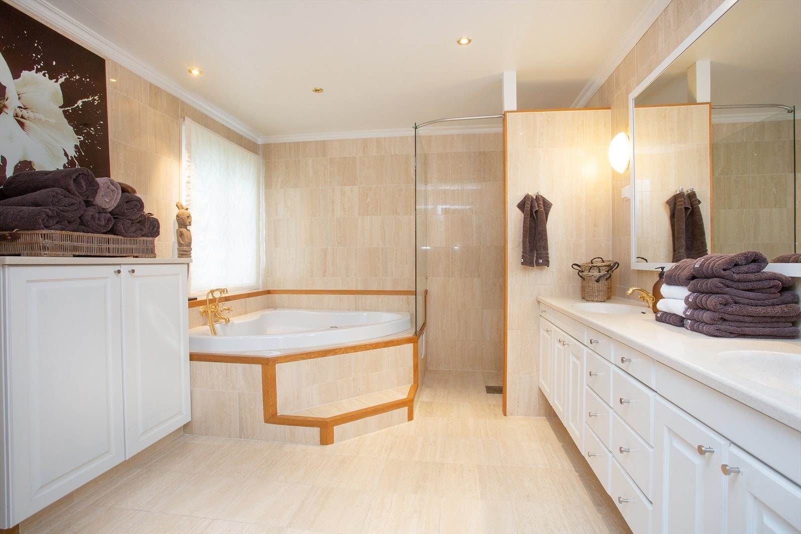 Badet i 1.etajse er flislagt på gulv og vegg i matcende flis, hjørnebadekar, dusj og baderomsinnredning med dobbel vask Galleribilde