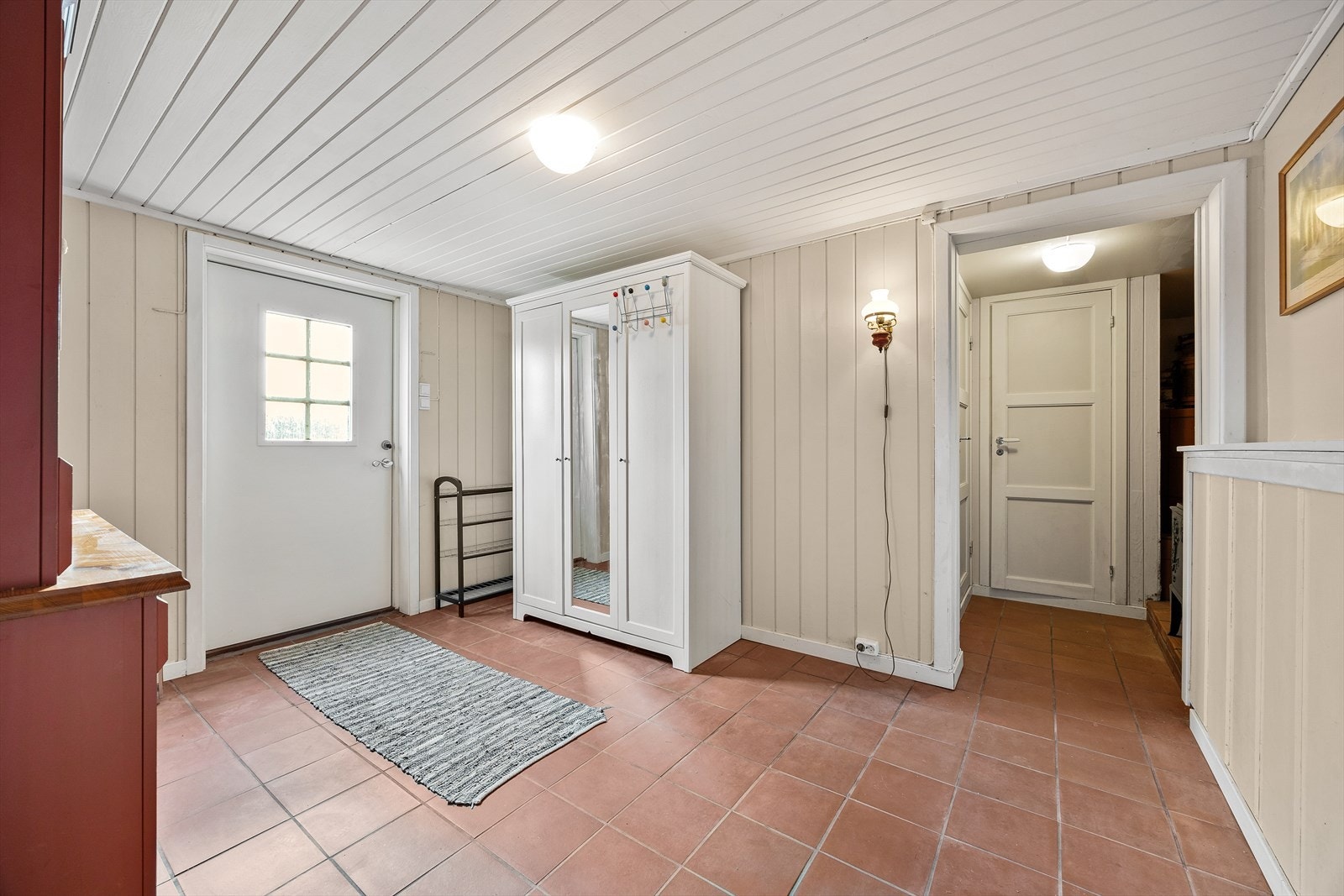 Inngangsparti med flislagt gulv og panelte overflater. Galleribilde