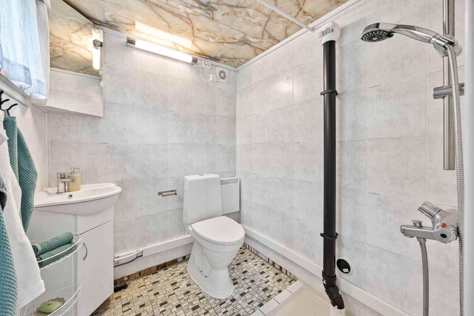 Badet innehar toalett, servant med skap og dusjnisje med forheng. Speil og belysning. Galleribilde