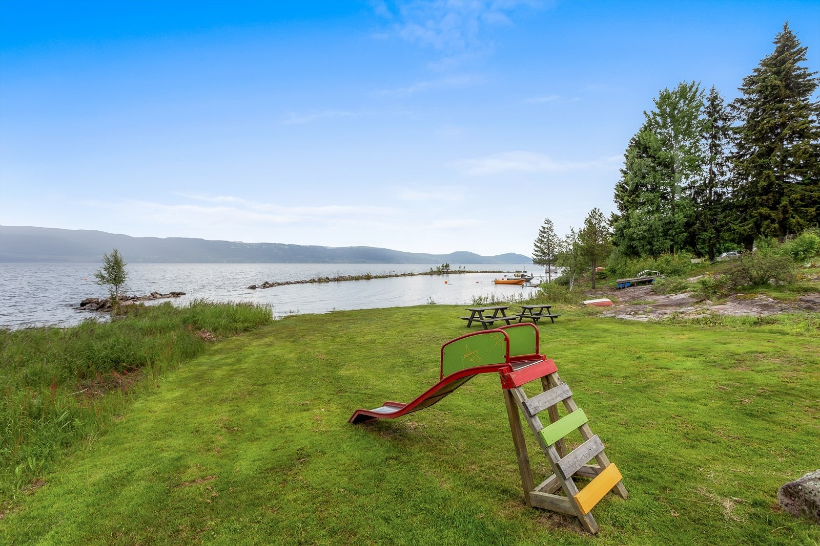 Stor gressplen ved vannet, ideelt for lek og avslapning. Galleribilde