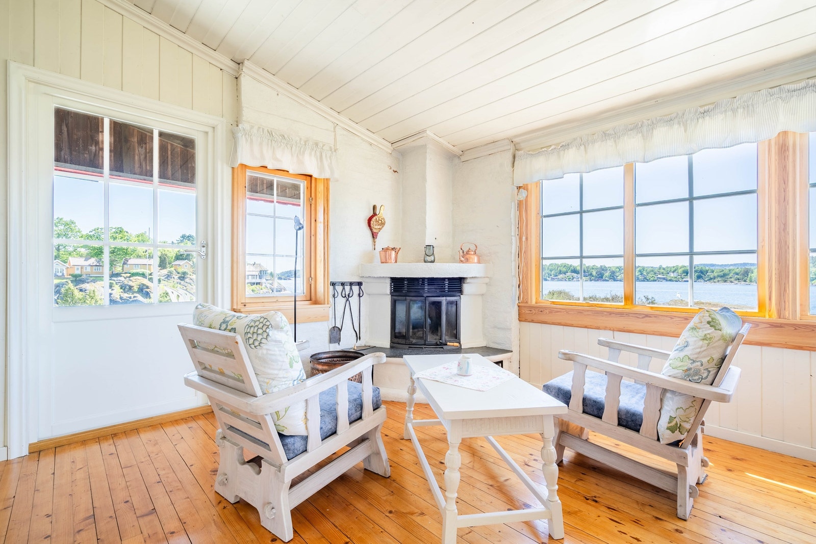 Stua fremstår som lys med malt trepanel og store vindusflater. Her kan du slappe av, se utover sjøen og fyre i peisen. Galleribilde