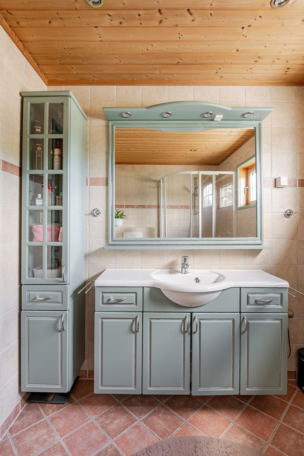 Flott baderomsinnredning med profilerte fronter og heldekkende servant, stort speil med belysning over, samt ekstra høyskap ved siden av. Baderommet er også utstyrt med dusjhjørne med skyvedører og vegghengt toalett. Galleribilde