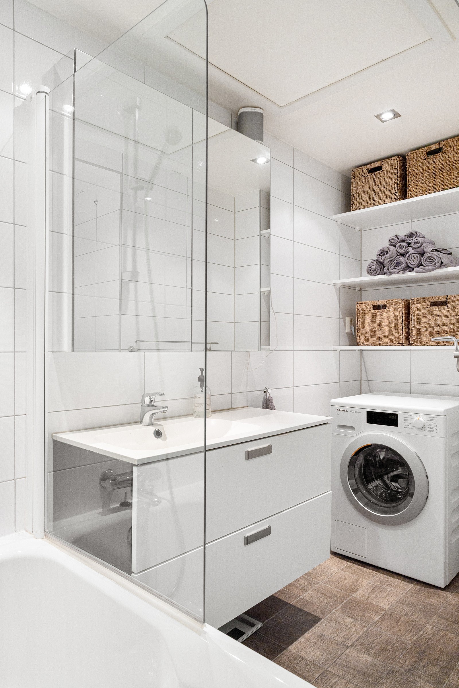 Stilren baderomsinnredning med tilhørende speilskap som harmonerer med resten av rommet samt også opplegg for vaskemaskin. Galleribilde