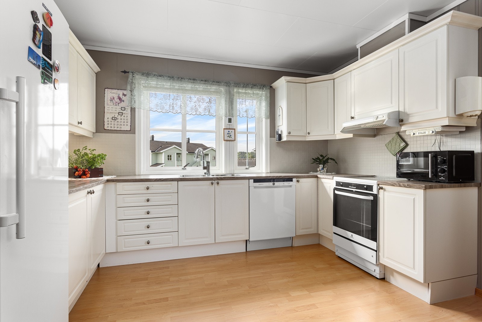 Kjøkkenet er lyst og klassisk med profilerte fronter og en praktisk, slitesterk benkeplate i laminat. Her er det godt med skap- og benkeplass, samt plass til frittstående kjøleskap, komfyr og oppvaskmaskin. Galleribilde