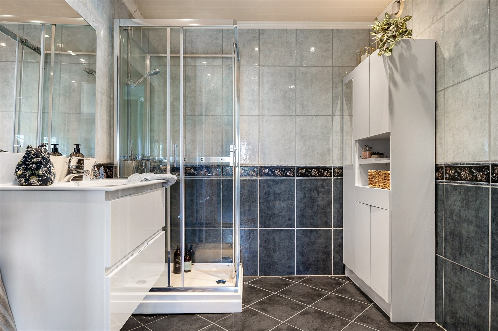 Flislagt bad med praktisk dusjkabinett og romslig oppbevaring. Galleribilde