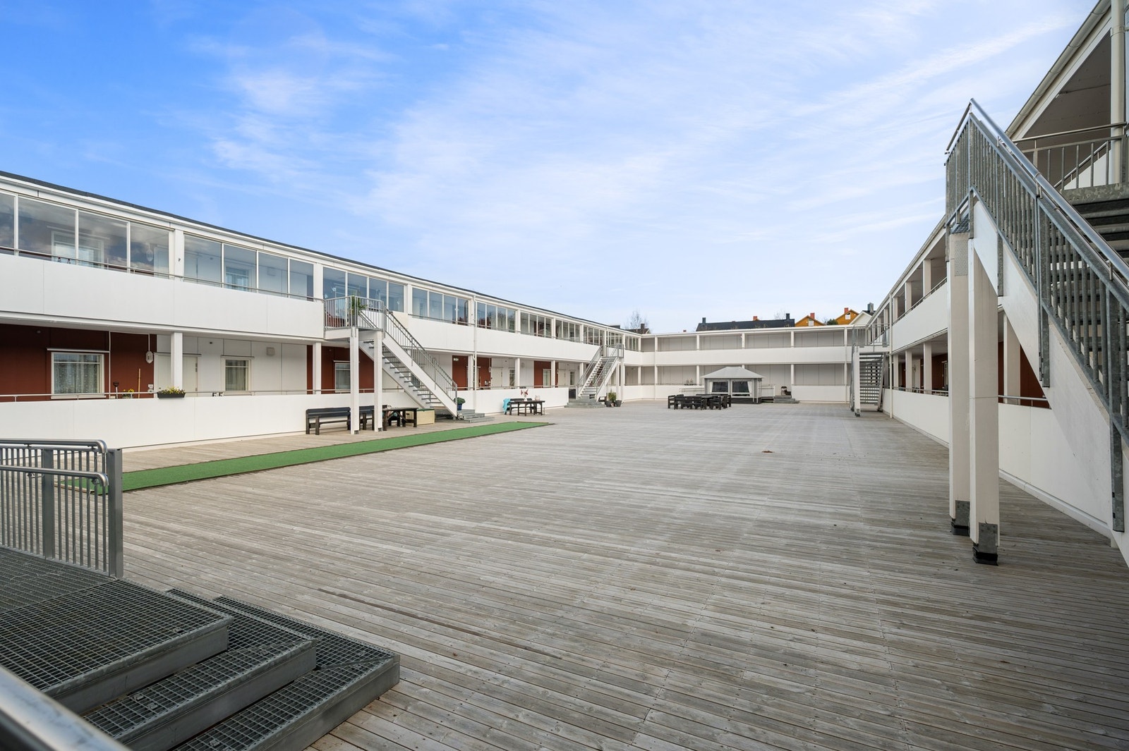 Felles bakgård for beboerne med stort terrasseområde og sittebenker Galleribilde