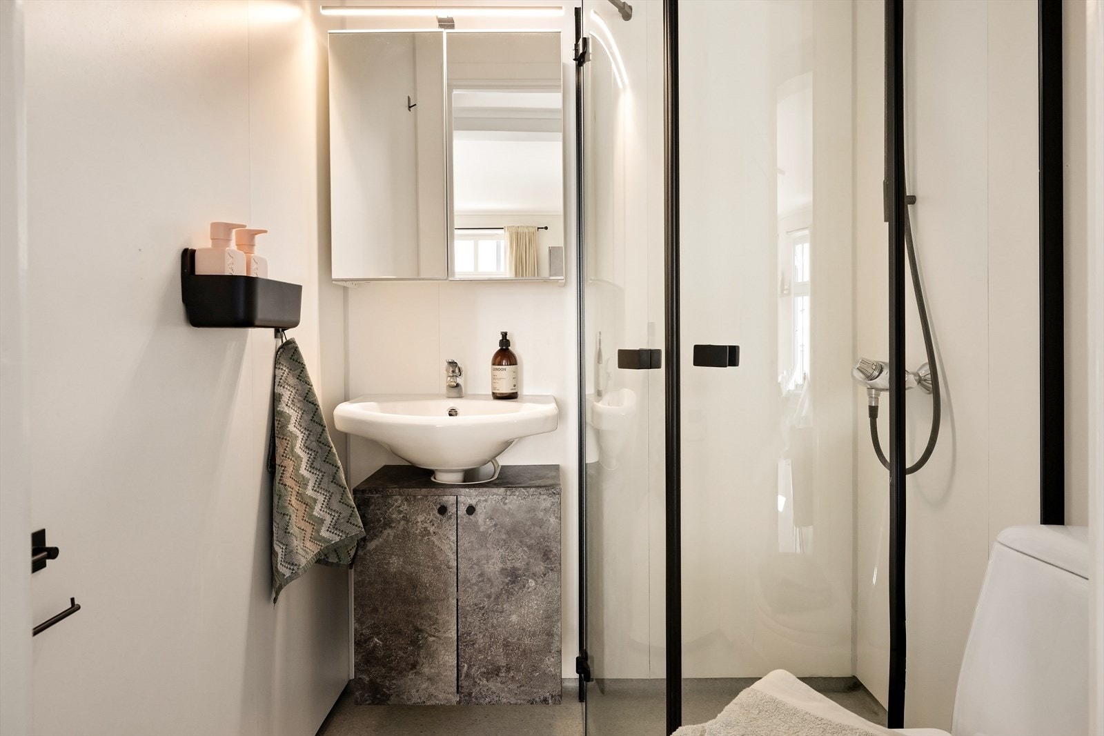 Badeommet er pent utformet med belegg og varme i gulvet, baderomsinnredning med rikelig skapplass og dusjhjørne med skyvbare dører i herdet glass. Galleribilde