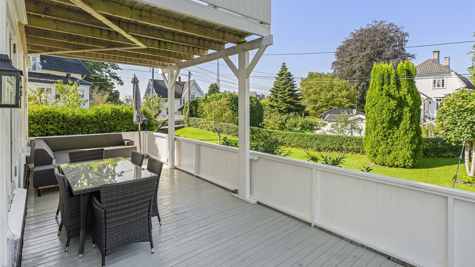 Fin og romslig veranda med ettermiddagssol og grønn utsikt over hagen Galleribilde