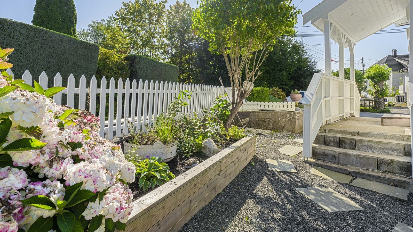 Overbygget inngangsparti og fine blomsterbed Galleribilde