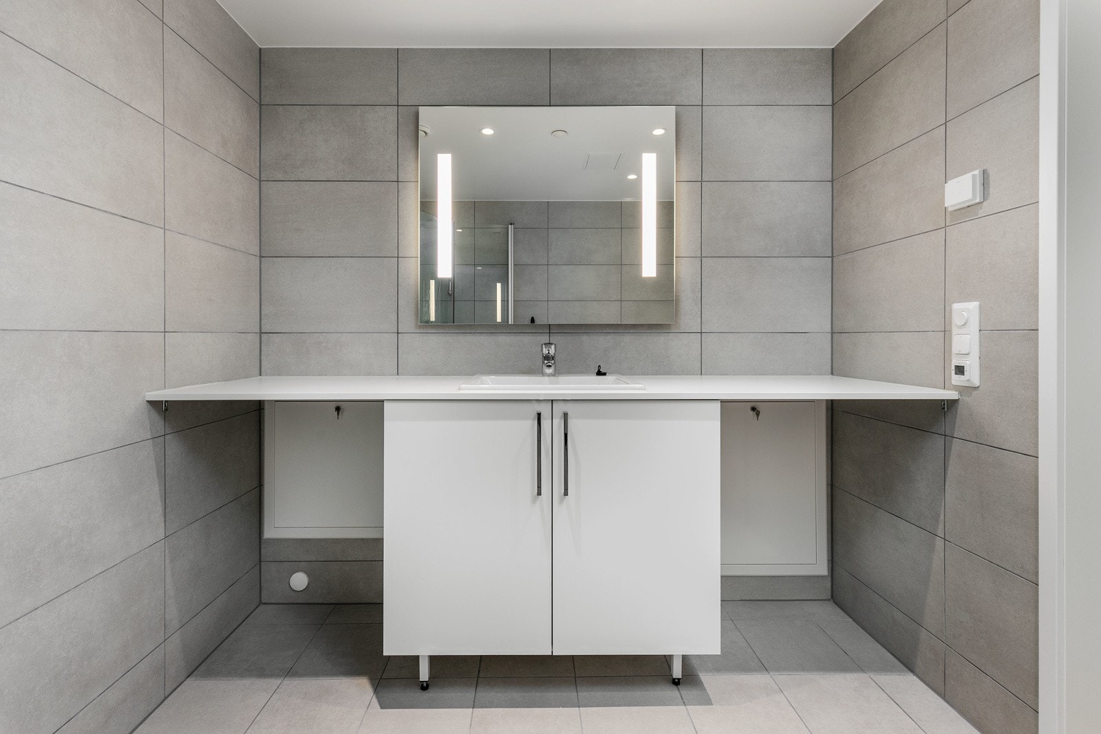 Badet har vegghengt toalett med innbygget sisterne, servant med skapinnredning samt speil med belysning. Galleribilde