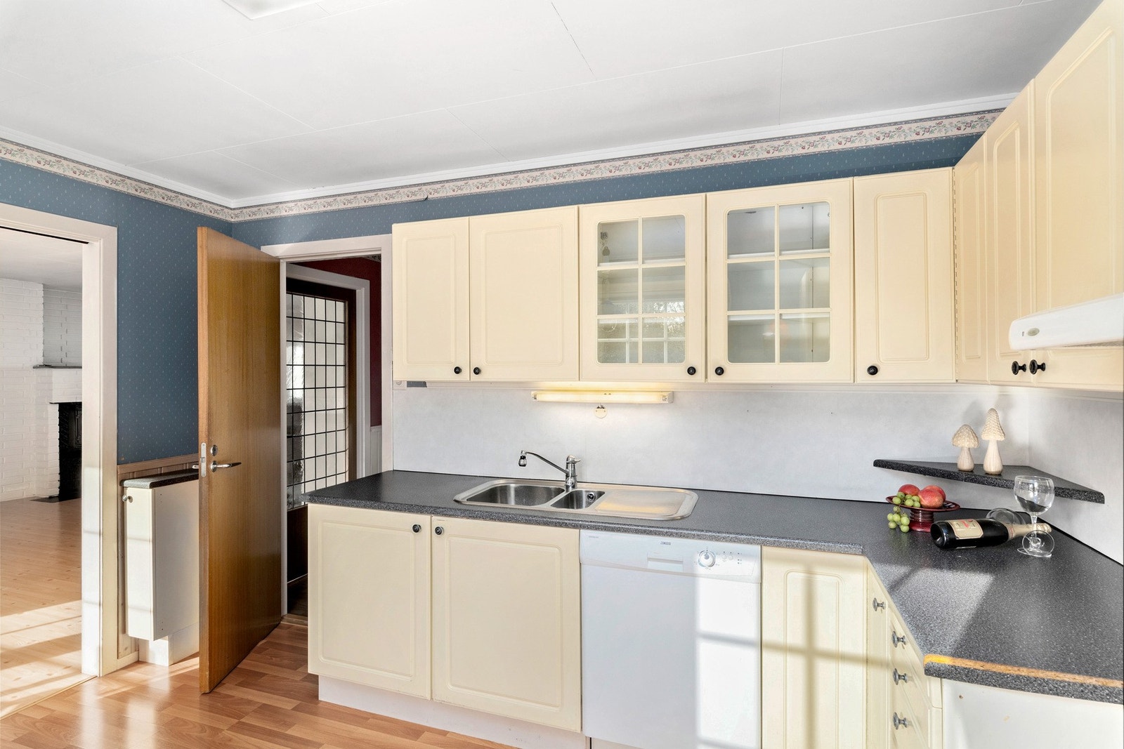 Koselig kjøkken med elfenbensfargerde fronter, kjøkkenventilator med avtrekk ut. Galleribilde