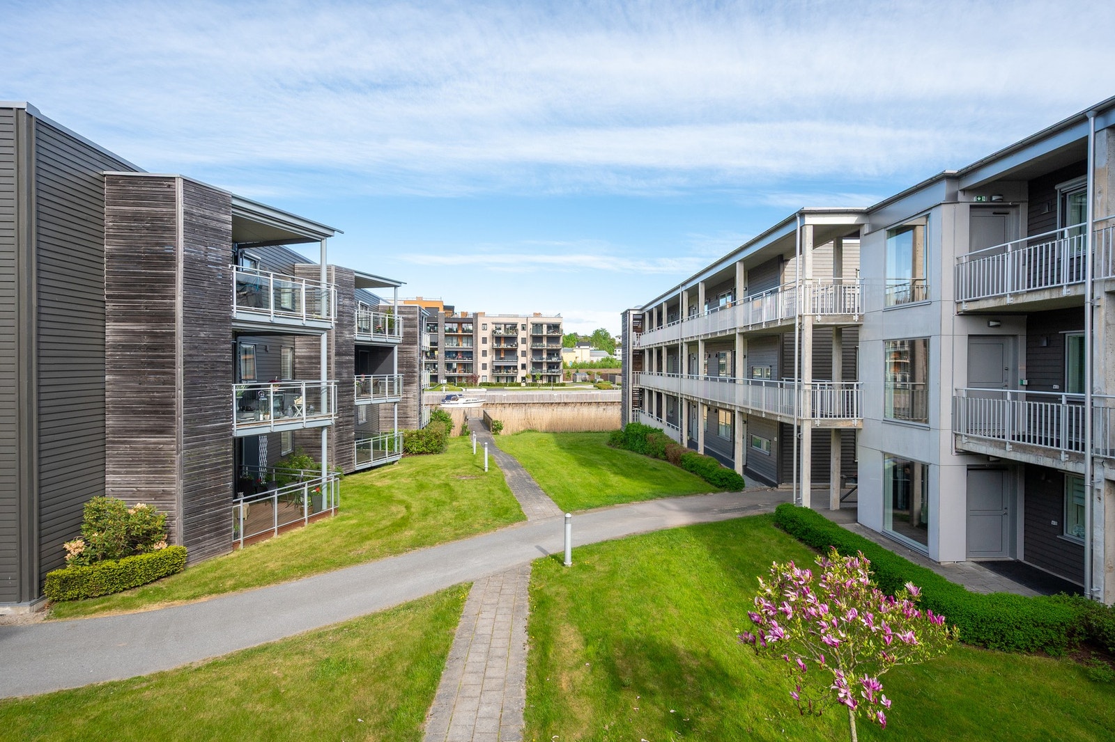 Tomten er parkmessig opparbeidet med gressplen, gangveier og prydbeplantning mellom husene og ned til kaikanten med bryggepromenaden Galleribilde