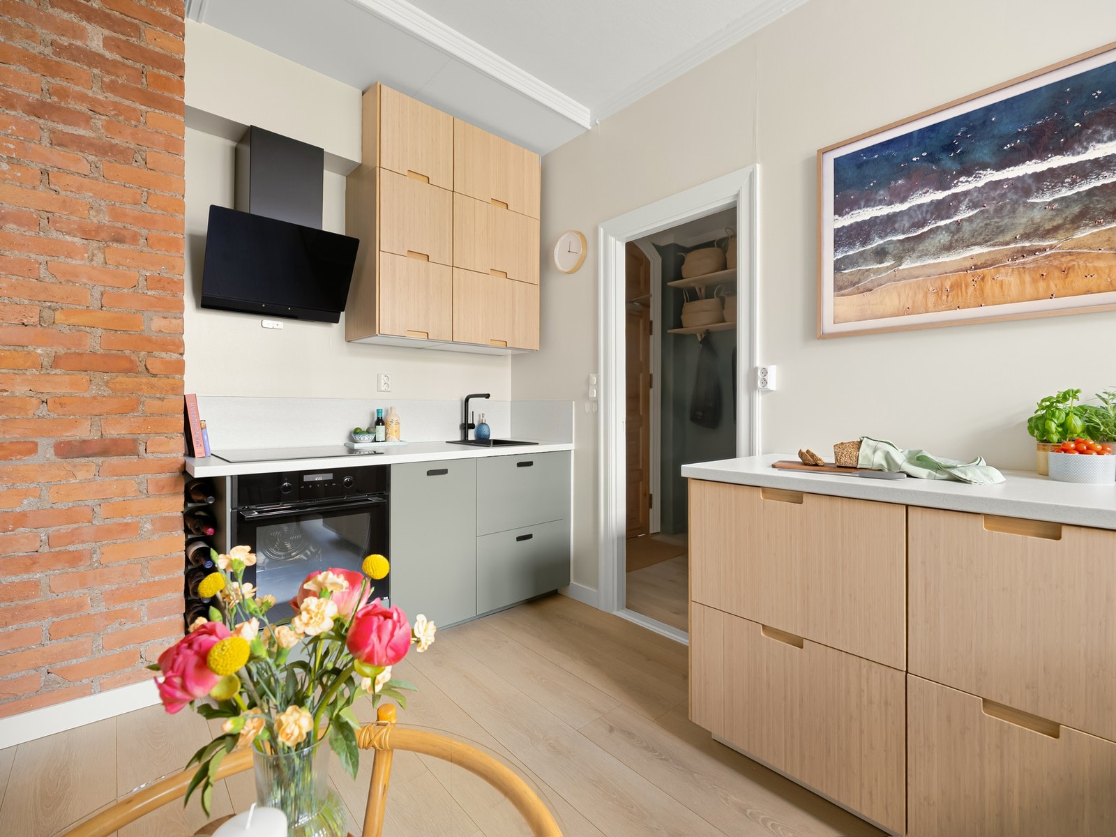 Den åpne kjøkken- og stueløsningen gjør dette til et sosialt allrom og er det naturlige samlingspunktet i leiligheten. TV-en henger på veggen over kjøkkenbenken. Galleribilde