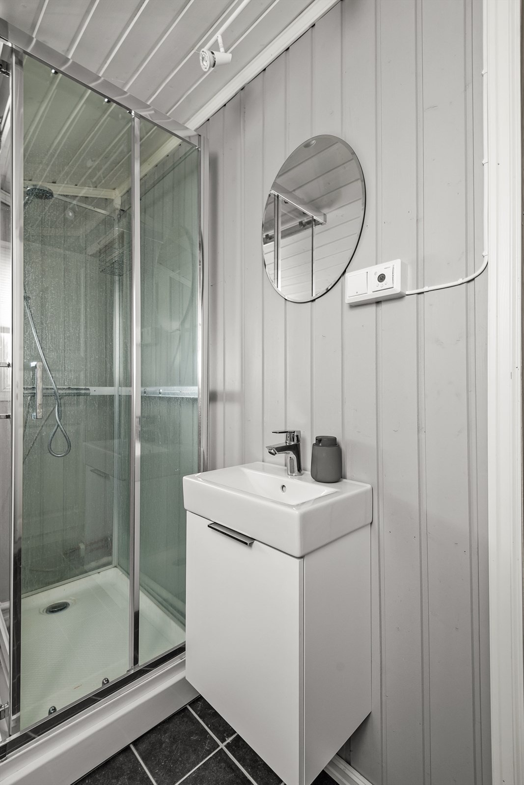 Dusjkabinett og enkel innredning med servant, underskap og speil Galleribilde