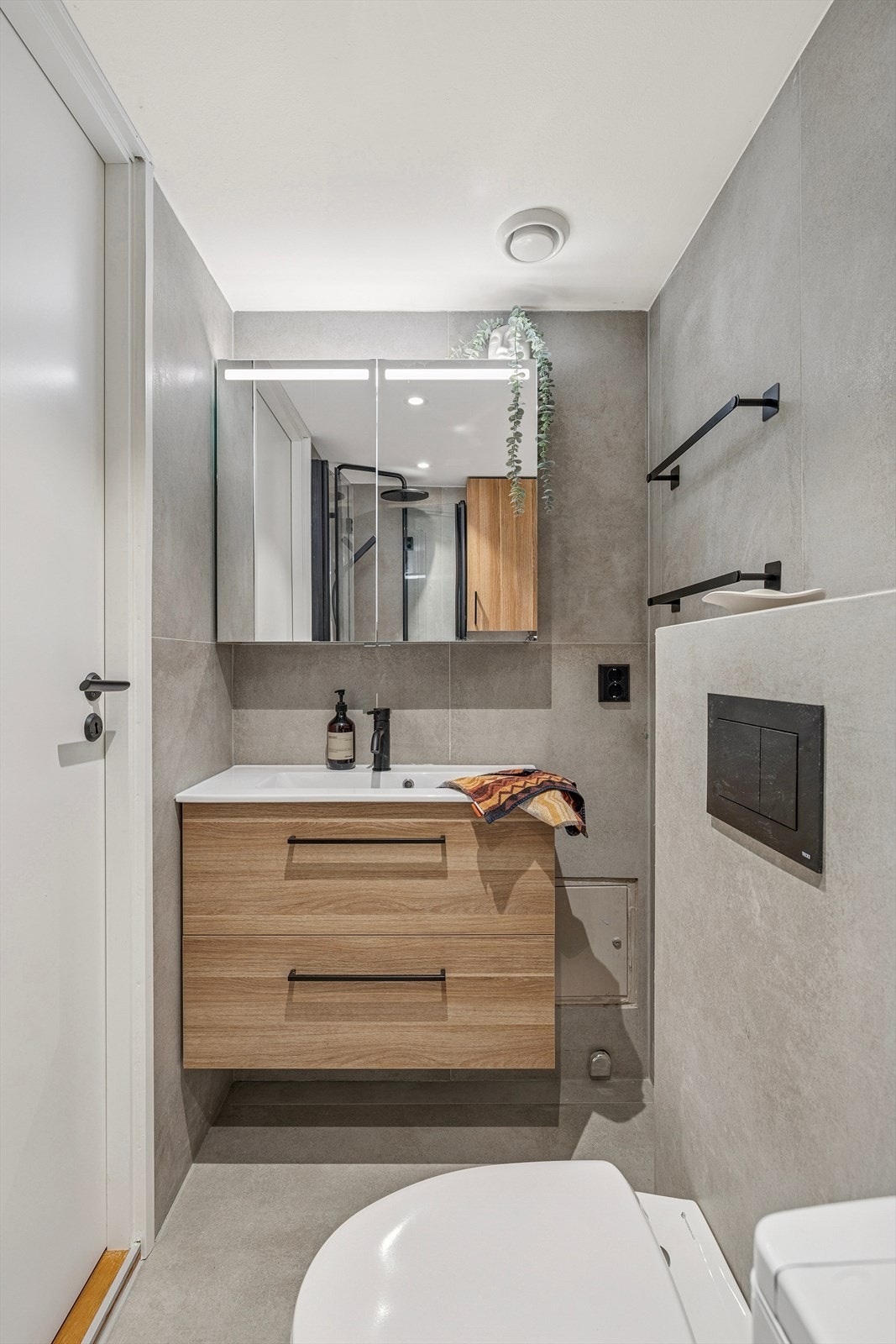 Her finner du stilren innredning med servant, vegghengt toalett, dusjhjørne med foldedører i glass og moderne armatur og opplegg for vaskemaskin. Galleribilde