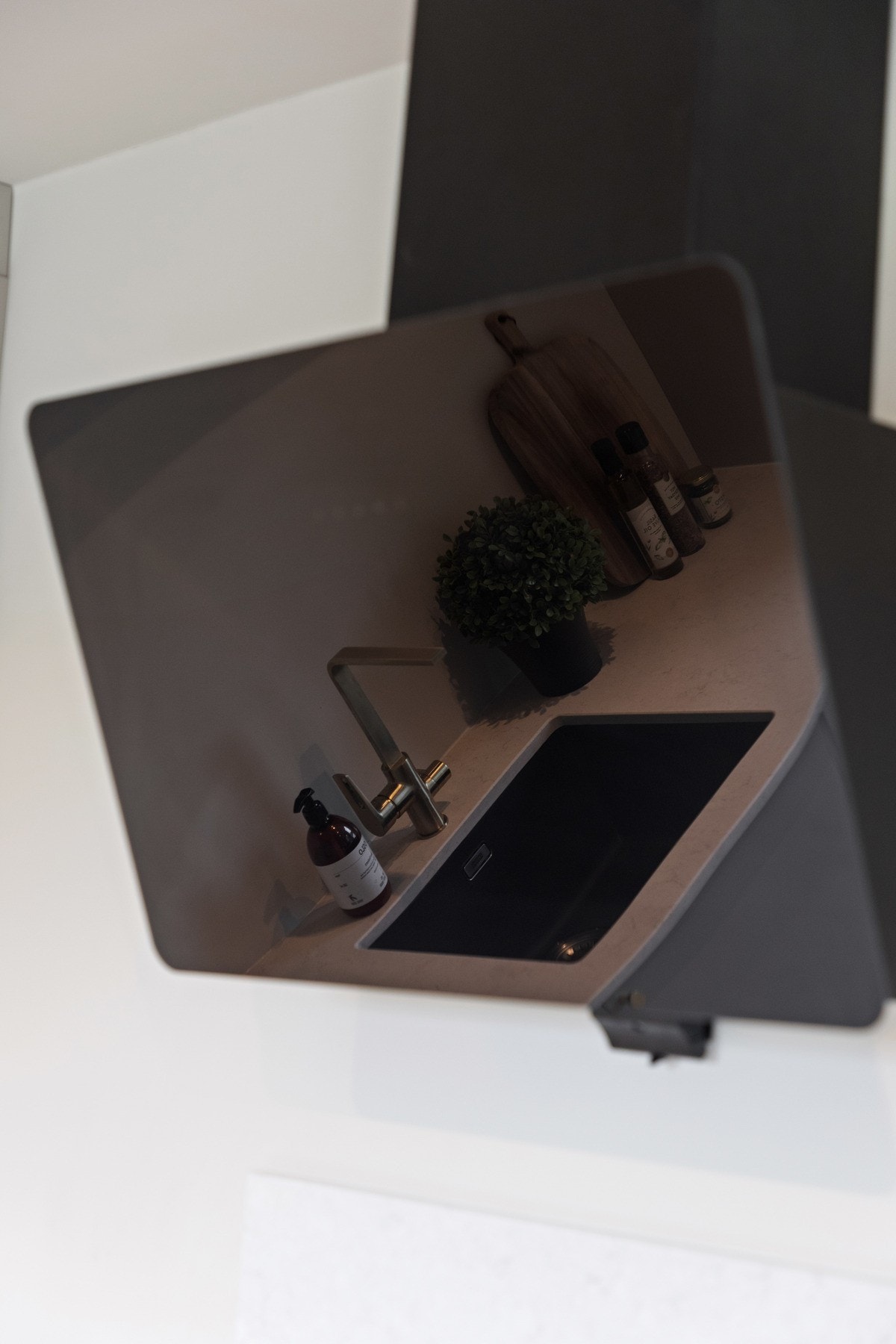Kjøkkenet har integrert stekeovn, induksjonstopp, oppvaskmaskin og kjøleskap, samt en sort ventilator og en hvit plate som backsplash. Galleribilde