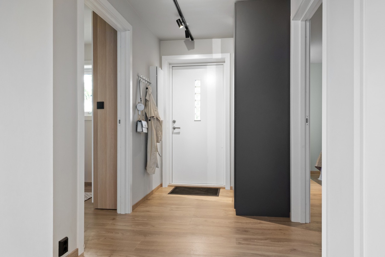 Entré med pent laminatgulv, lysmalte vegger og listefri himling med spotbelysning. Galleribilde