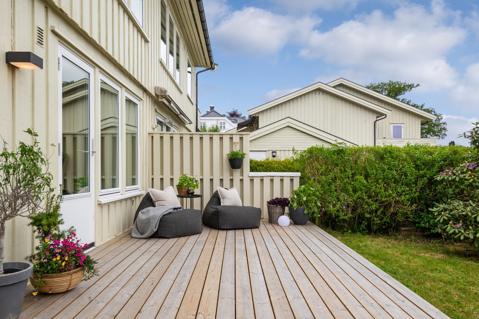 Terrassen har dekke av terrassebord, levegg mot naboen og god plass til en komfortabel møbelgruppe. Galleribilde