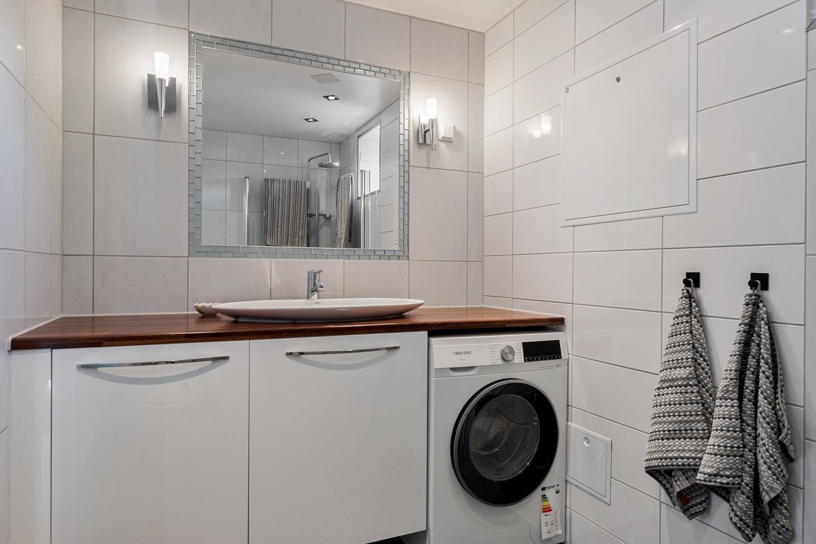 Badet er utstyrt med foldedører i dusj, toalett og baderomsinnredning med servant samt belyst speil. Det er også opplegg for vaskemaskin Galleribilde